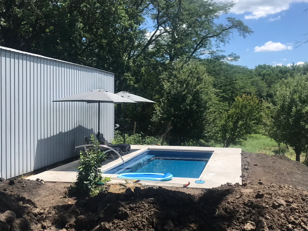 Backyard pool and deck seating area built by Custom Pools of Mahomet
