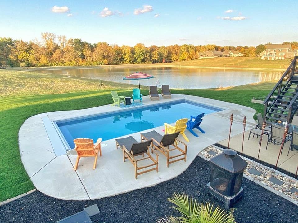 A pool with chairs and a fire pit in the middle of it.